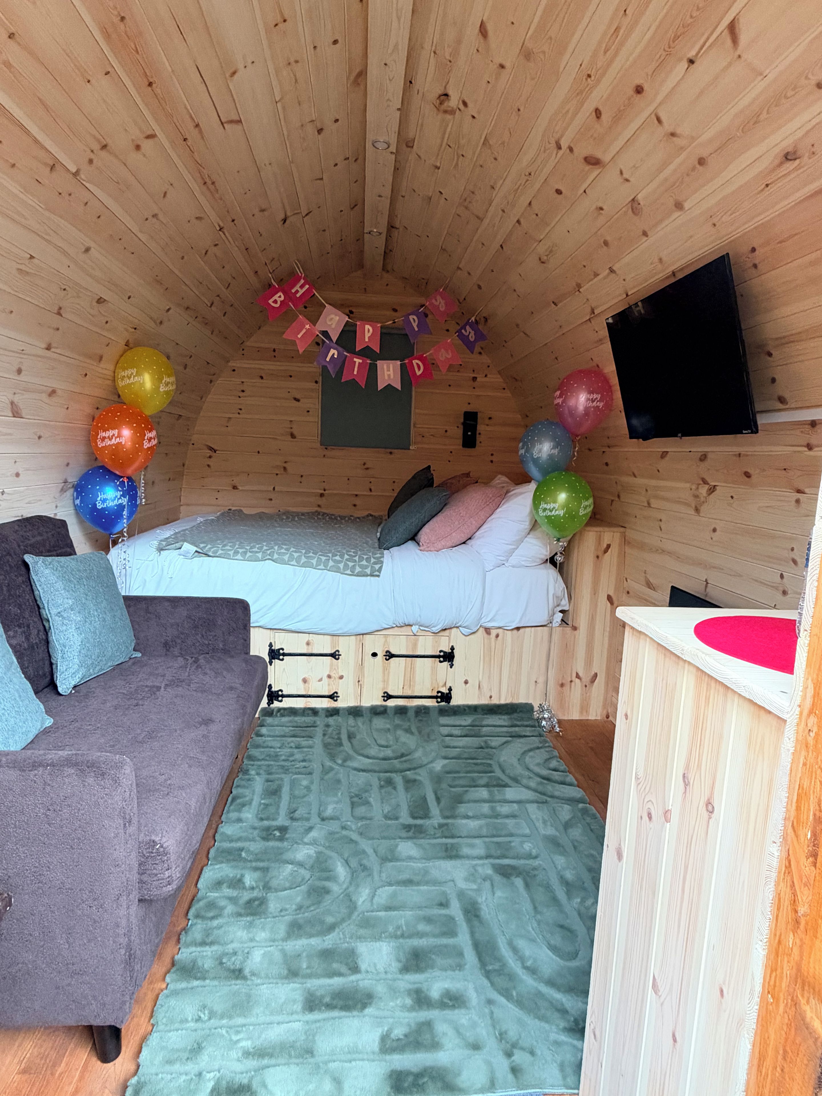 Une pièce confortable avec un lit, un canapé, un téléviseur à écran plat et un plafond en bois.