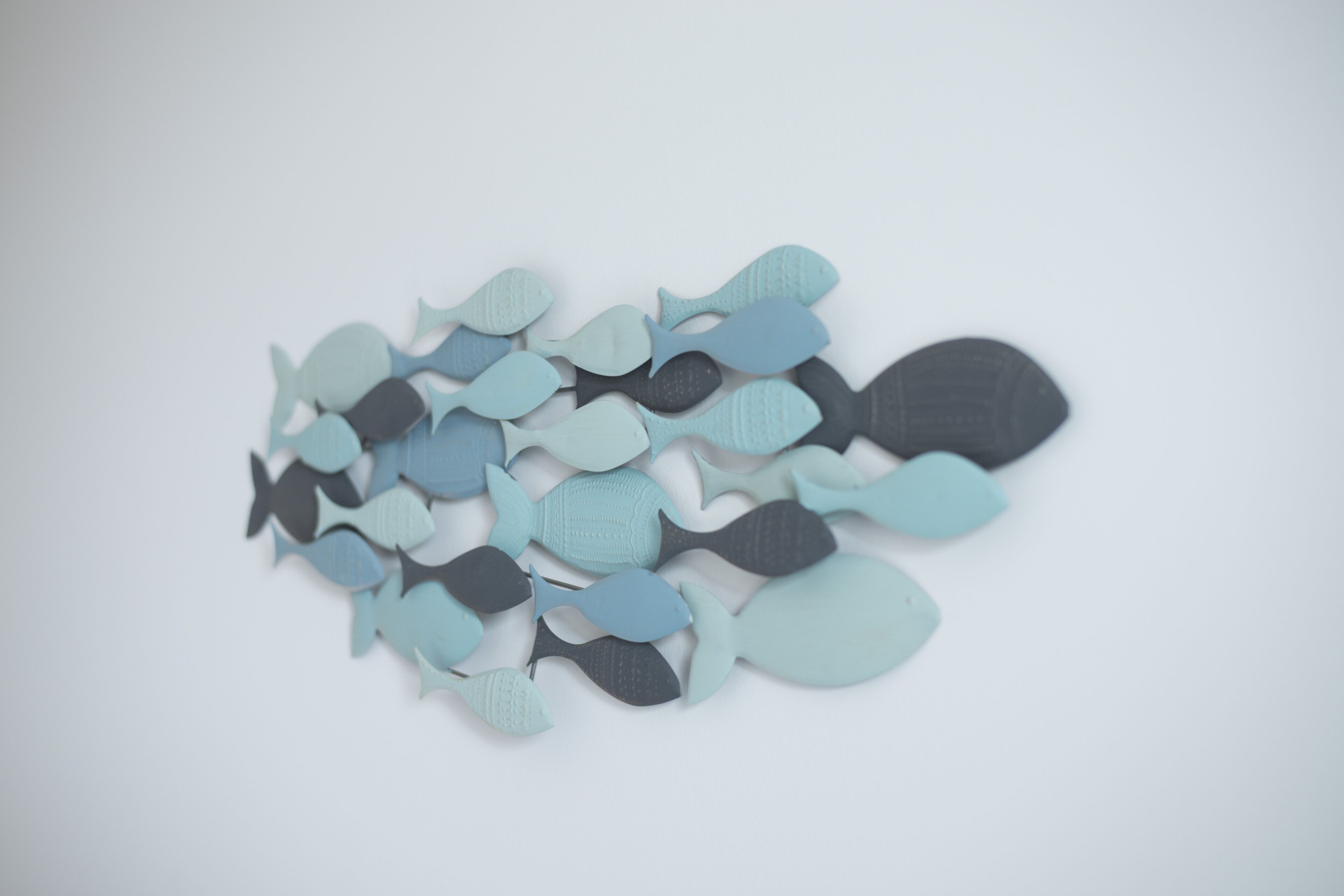 Une collection de découpes de poissons en papier, de différentes tailles et dans diverses nuances de bleu et de gris.