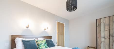 A bedroom with a bed, a blue and white blanket, and two wall-mounted lights.