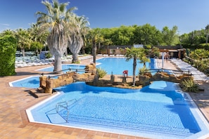 Une grande piscine extérieure entourée de palmiers et dotée de chaises longues.