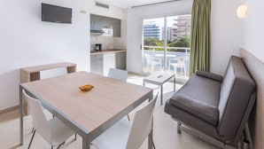 Een knus verblijf met een kitchenette, een eethoek, een bank en een balkon met uitzicht op de stad.