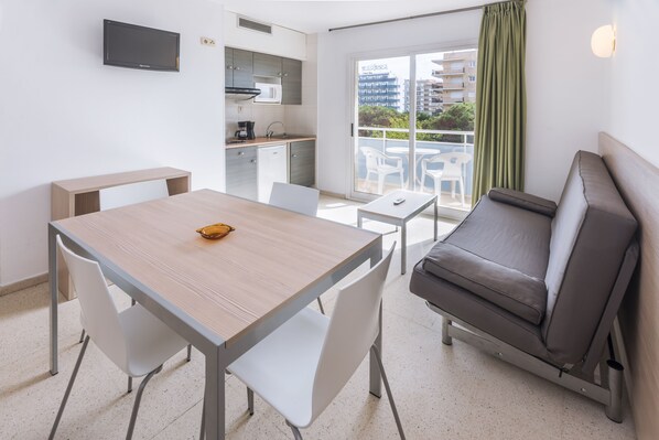 Un espace de vie compact comprenant une kitchenette, un coin repas, un canapé et un balcon offrant une vue sur la ville.