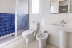 Une salle de bain équipée de toilettes, d’un bidet et d’un lavabo.