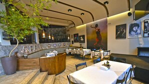 En restaurang med en modern inredning, med en central bardisk i trä, flera bord och inramade tavlor på väggarna.