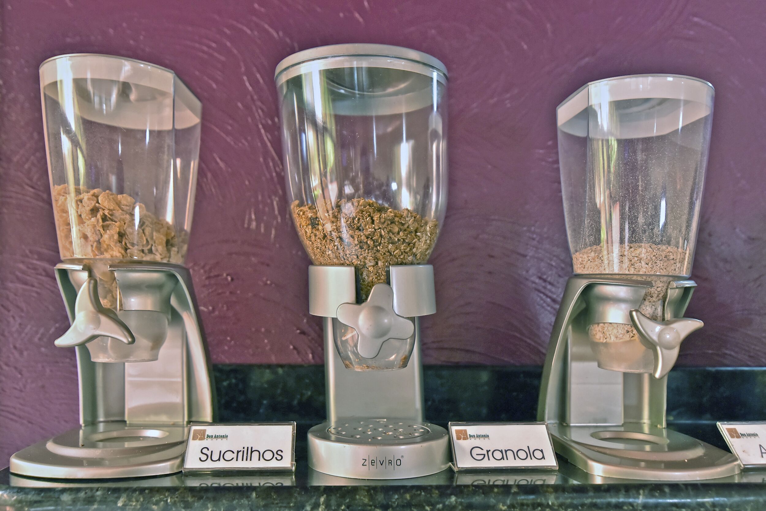 Three coffee grinders labeled Sucrinol, Zelevra, and Granola, with a purple wall in the background.