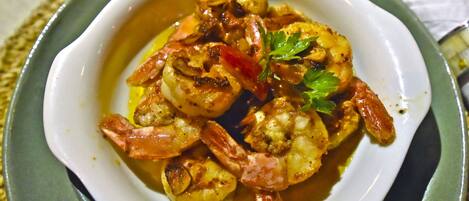A bowl of shrimp with vegetables and herbs.