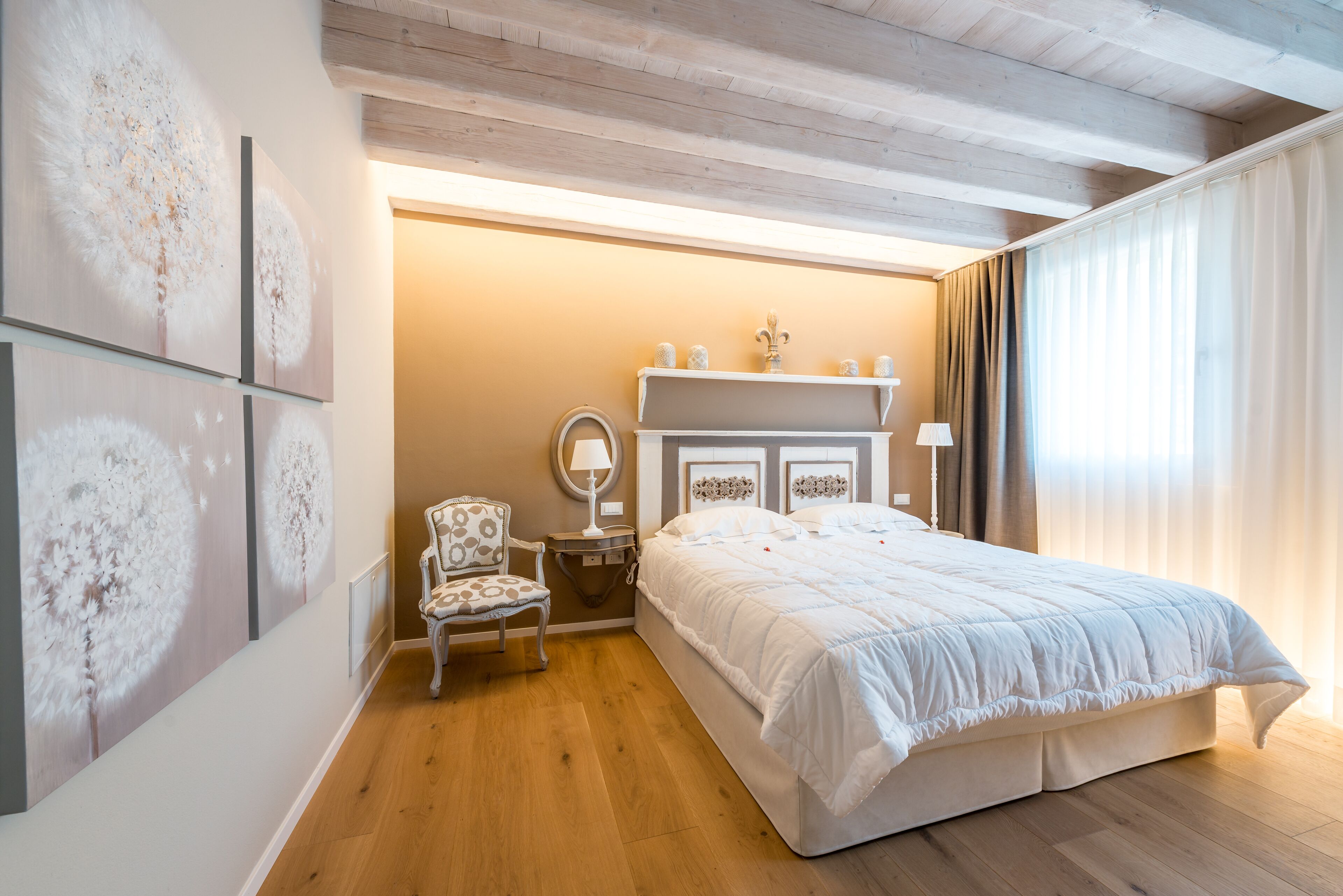 Un dormitorio con una cama grande, una silla, una mesita de noche, un espejo y una chimenea.