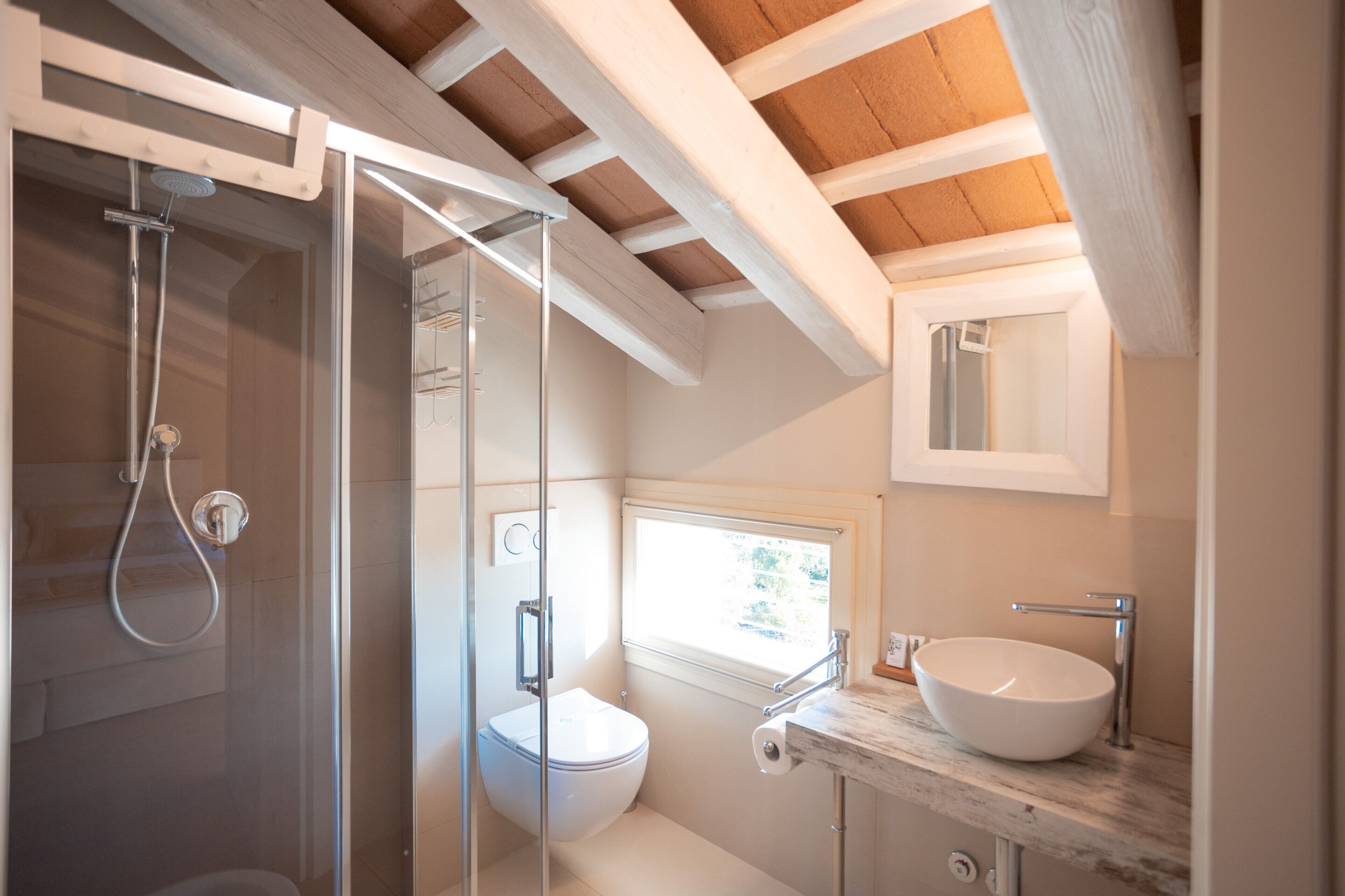 Un baño moderno con ducha de vidrio, inodoro blanco y lavamanos de mármol.