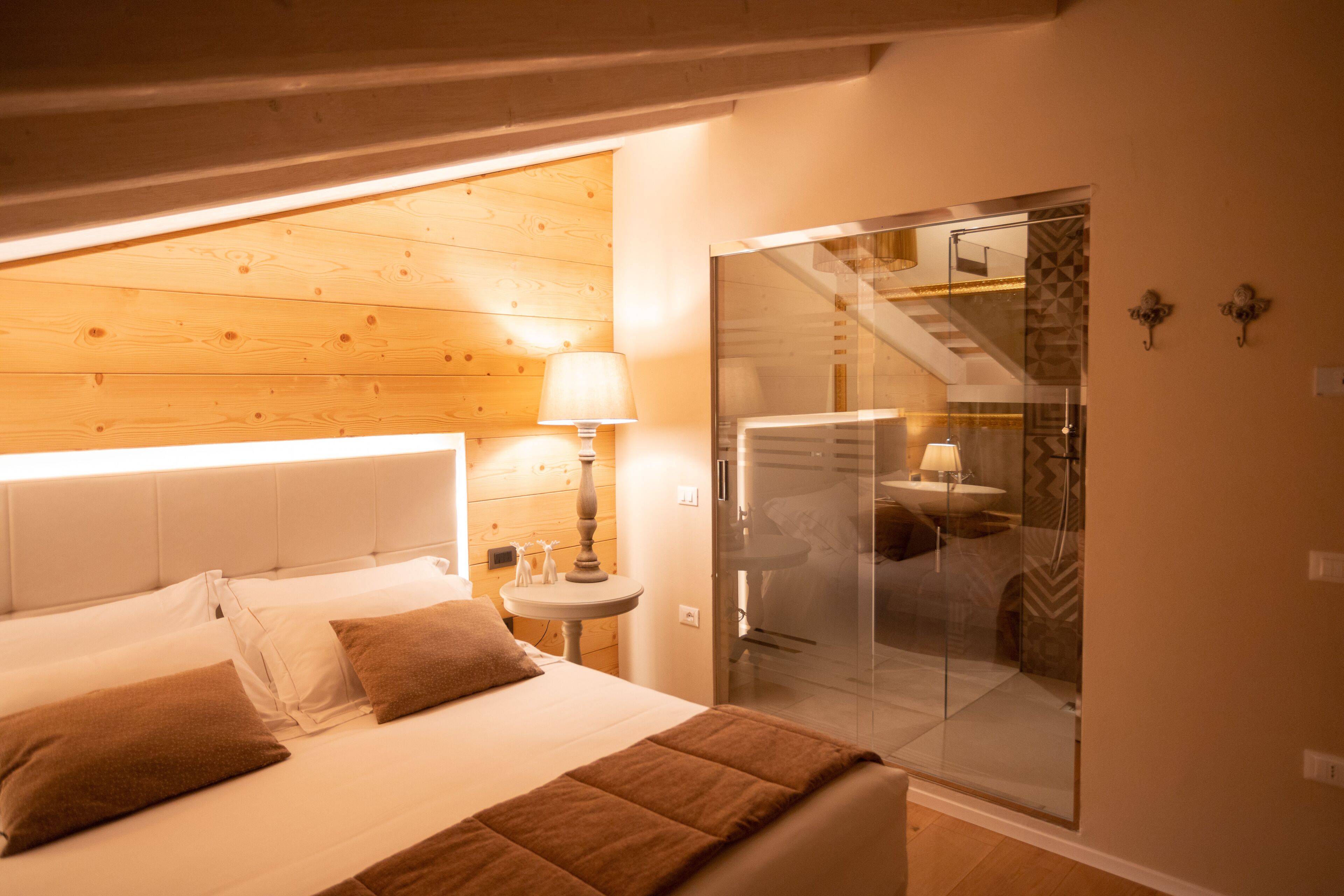 Un dormitorio con cama, mesita de noche con lámpara y cabina de ducha de vidrio.