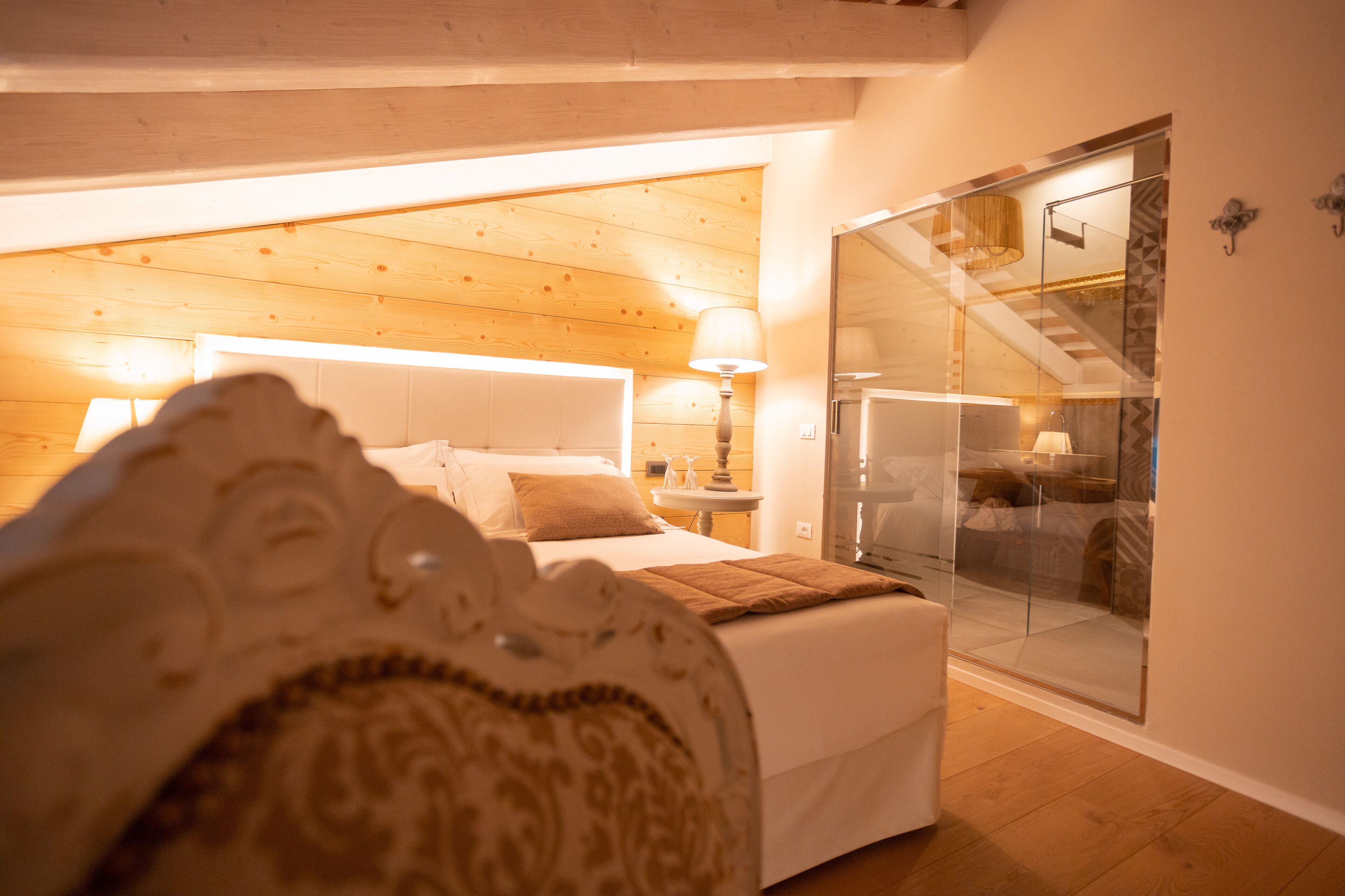 Ein Schlafzimmer mit Bett, Nachttisch, Lampe und einer Glastür zum Badezimmer.