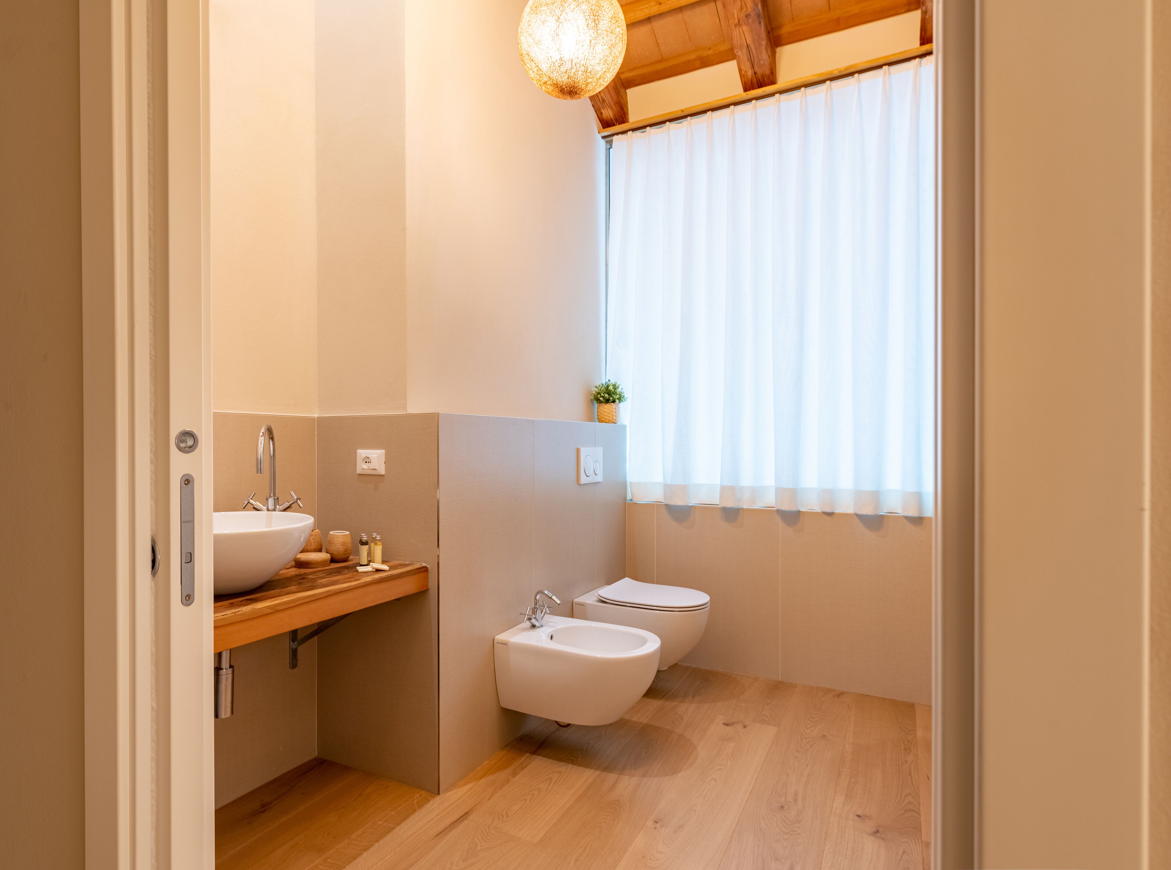 Un baño pequeño con tocador de madera, lavamanos, bidé e inodoro.