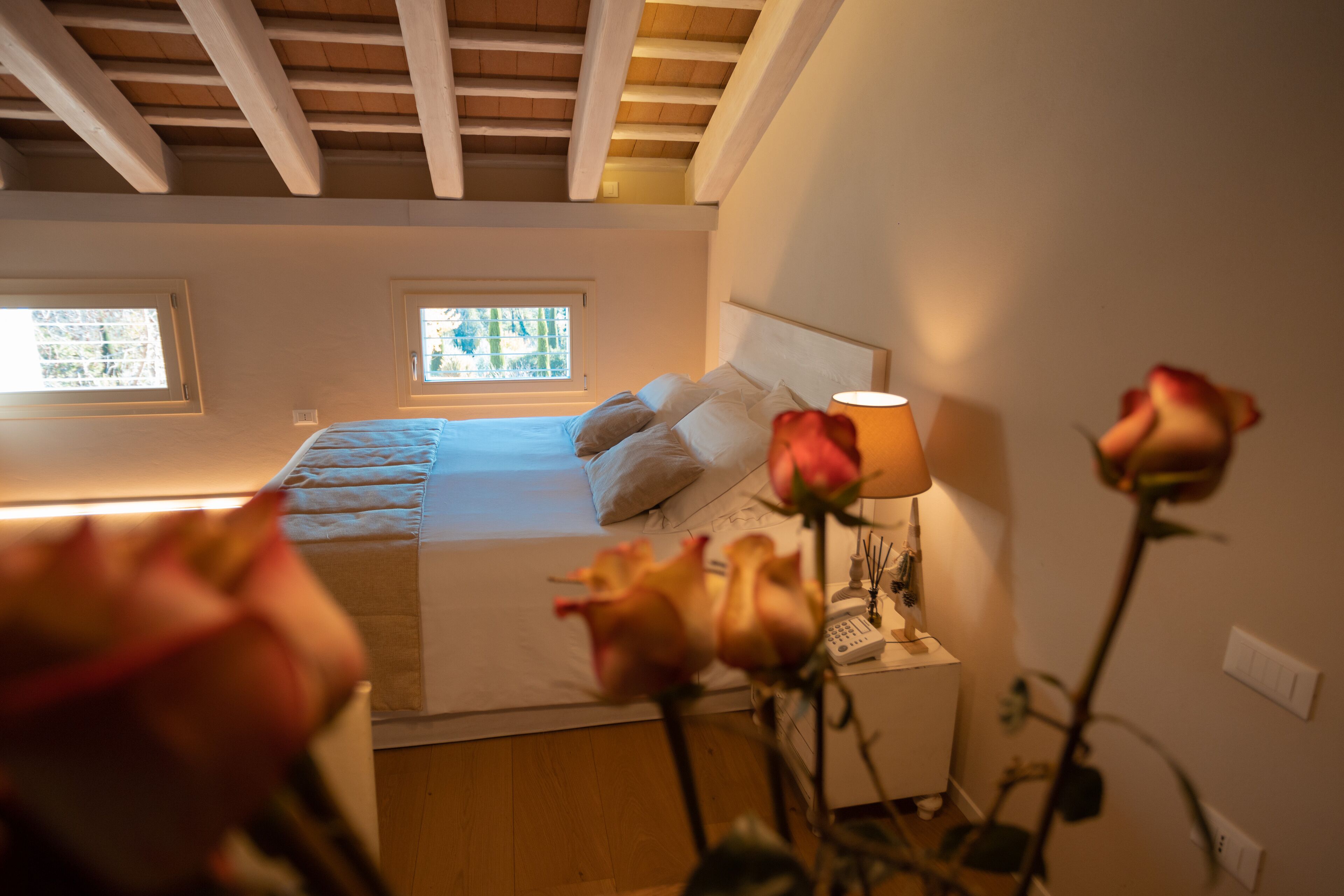 A bedroom with a bed, bedside lamp, and a window.