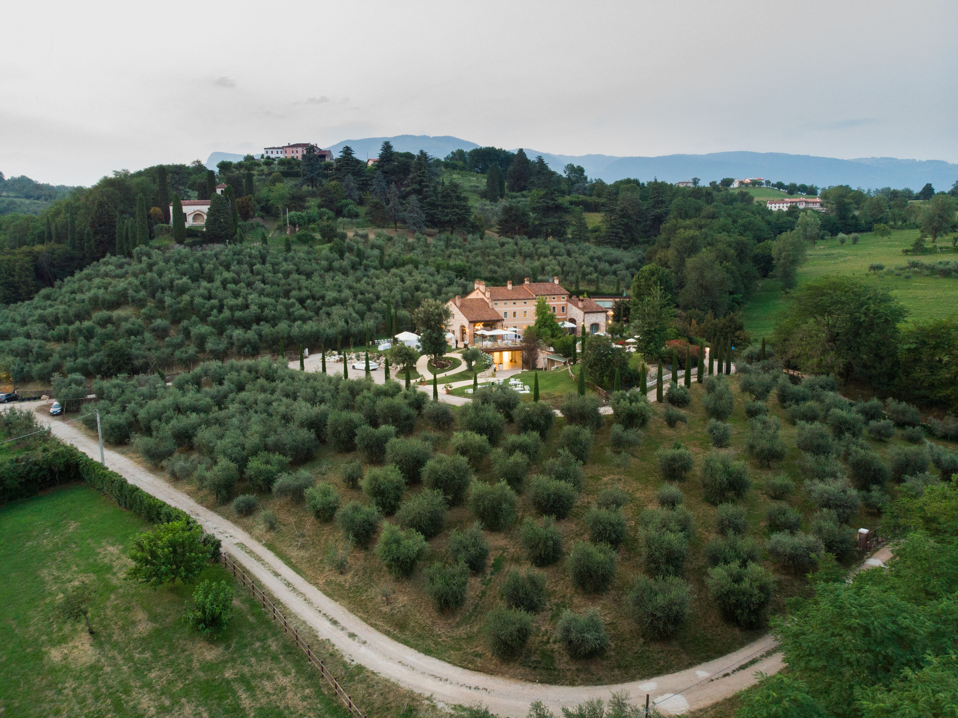 Une grande villa entourée d’oliveraies, accessible par un chemin sinueux.
