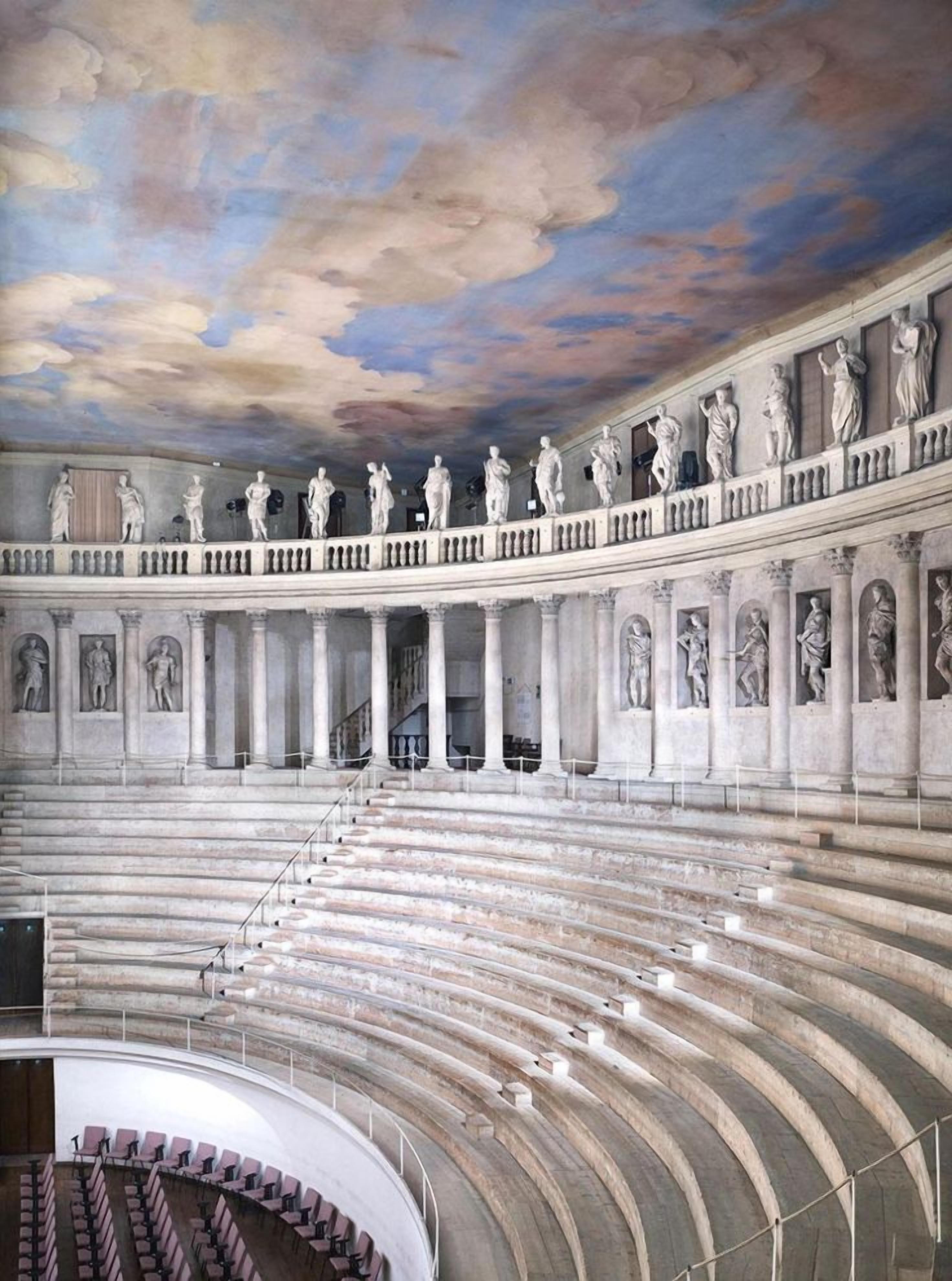 Un anfiteatro interior con disposición semicircular de asientos y una serie de estatuas en el nivel superior.