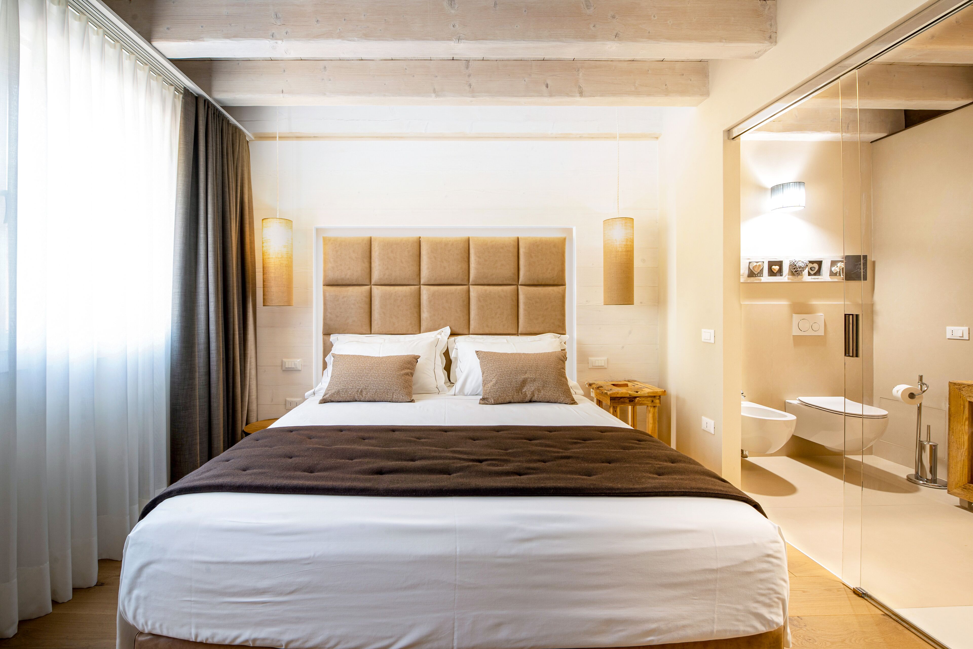 Una habitación de hotel con una cama grande, una mesita de noche, un espejo y un baño con lavamanos e inodoro.