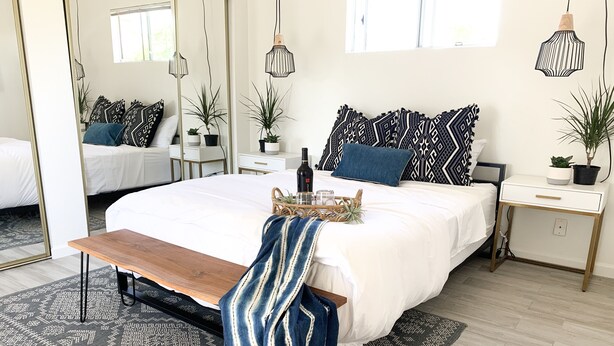 A modern bedroom with a large bed, bedside tables, a bench, and a mirror. - South Oceanside 1br/1bath, clean and beach close (Oceanside)