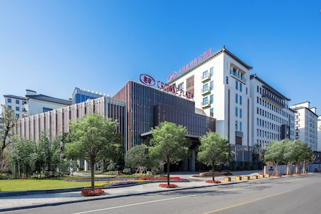 A modern hotel with a prominent sign, a landscaped entrance, and a clear sky.