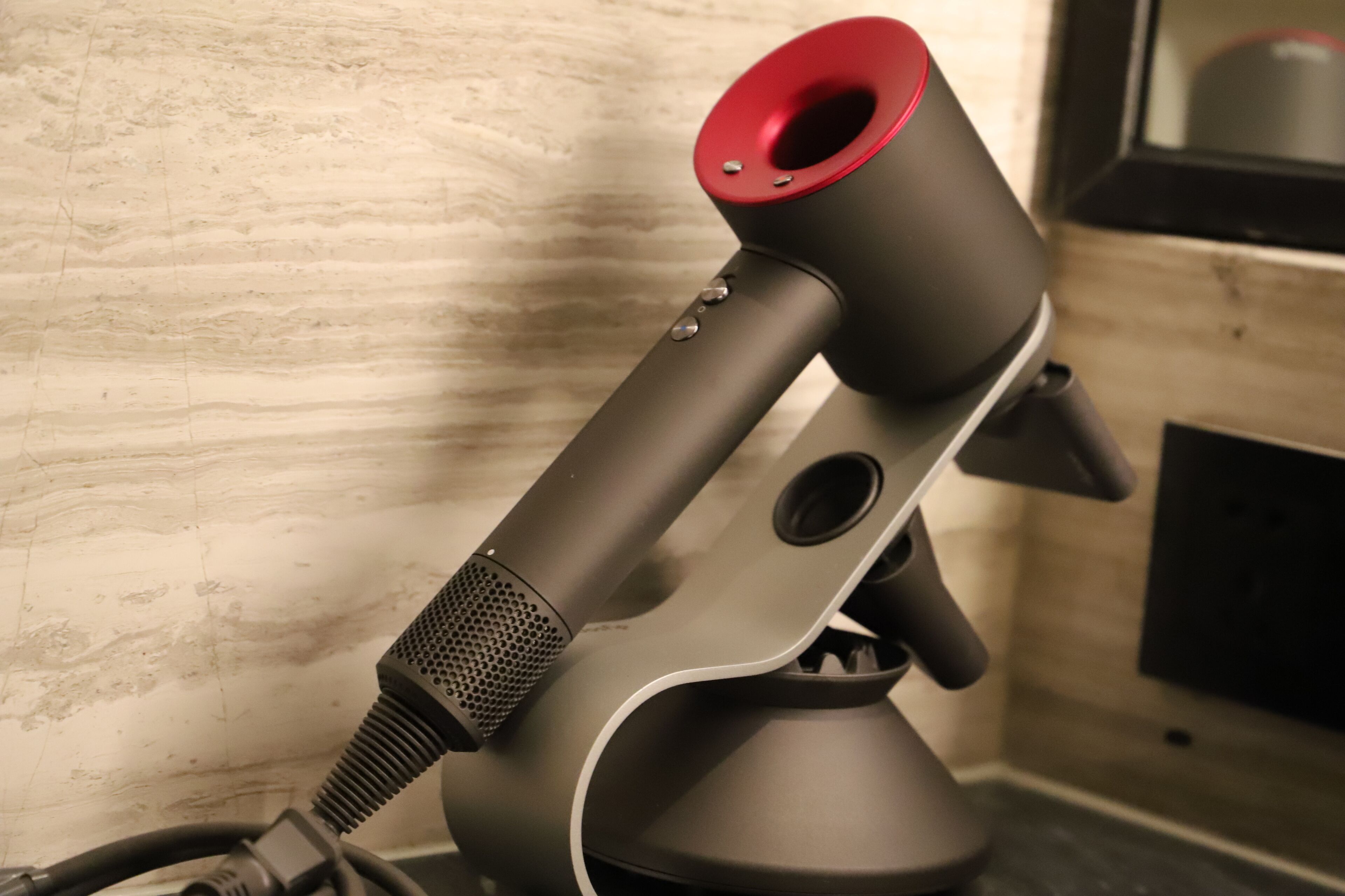 Un altavoz moderno y minimalista con un detalle rojo, sobre una pared con textura.