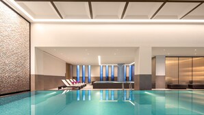 A modern indoor swimming pool with clear water, lounge chairs, and a contemporary design. - Crowne Plaza Wuzhen by IHG (Jiaxing)