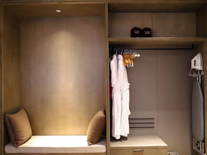 A hotel room with a bed, a seating area, a wardrobe, and a vanity with an iron. - Crowne Plaza Wuzhen by IHG (Jiaxing)