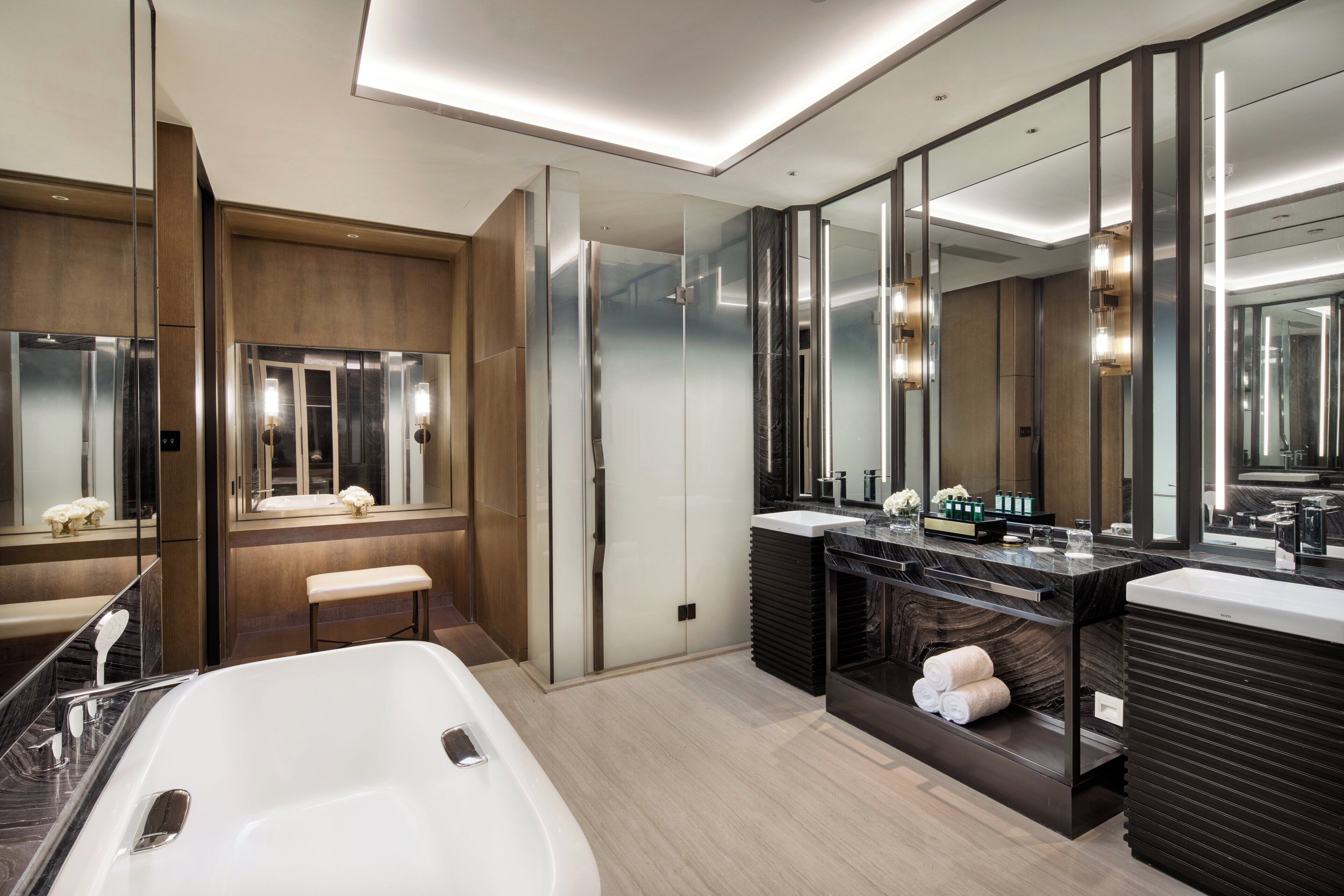 A modern bathroom with a large bathtub, two sinks, and a vanity with a mirror.
