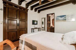 A bedroom with a large bed, wooden wardrobe, a television on a small table, and a framed picture on the wall. - Casa Granada 24 (Cancun)