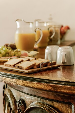 A breakfast setup with sliced bread, a pitcher of orange juice, and a glass of milk on a wooden table. - Casa Granada 24 (Cancun)
