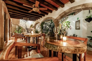 A cozy restaurant with wooden tables and benches, a ceiling fan, and potted plants. - Casa Granada 24 (Cancun)