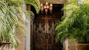 A grand entrance with a large wooden door, steps with blue and white patterned tiles, and potted plants on either side. - Casa Granada 24 (Cancun)