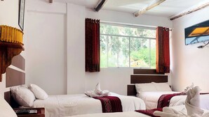 A hotel room with two beds, a TV, and a window with curtains.