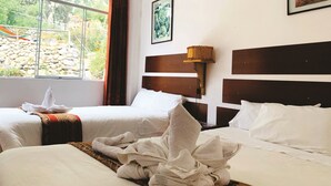 A hotel room with two beds, a large window with a view of greenery, a painting on the wall, and a bedside lamp.