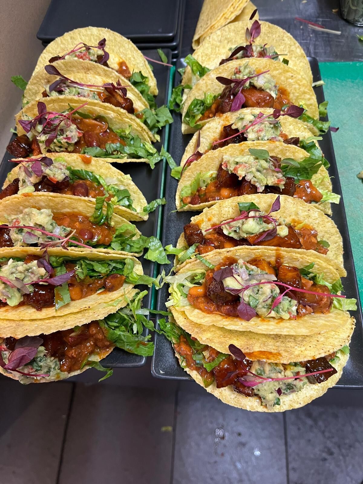 Un vassoio di tacos con diversi condimenti e una tovaglia verde.