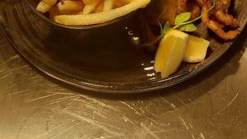 A plate with a fish fillet, fries, and bread.
