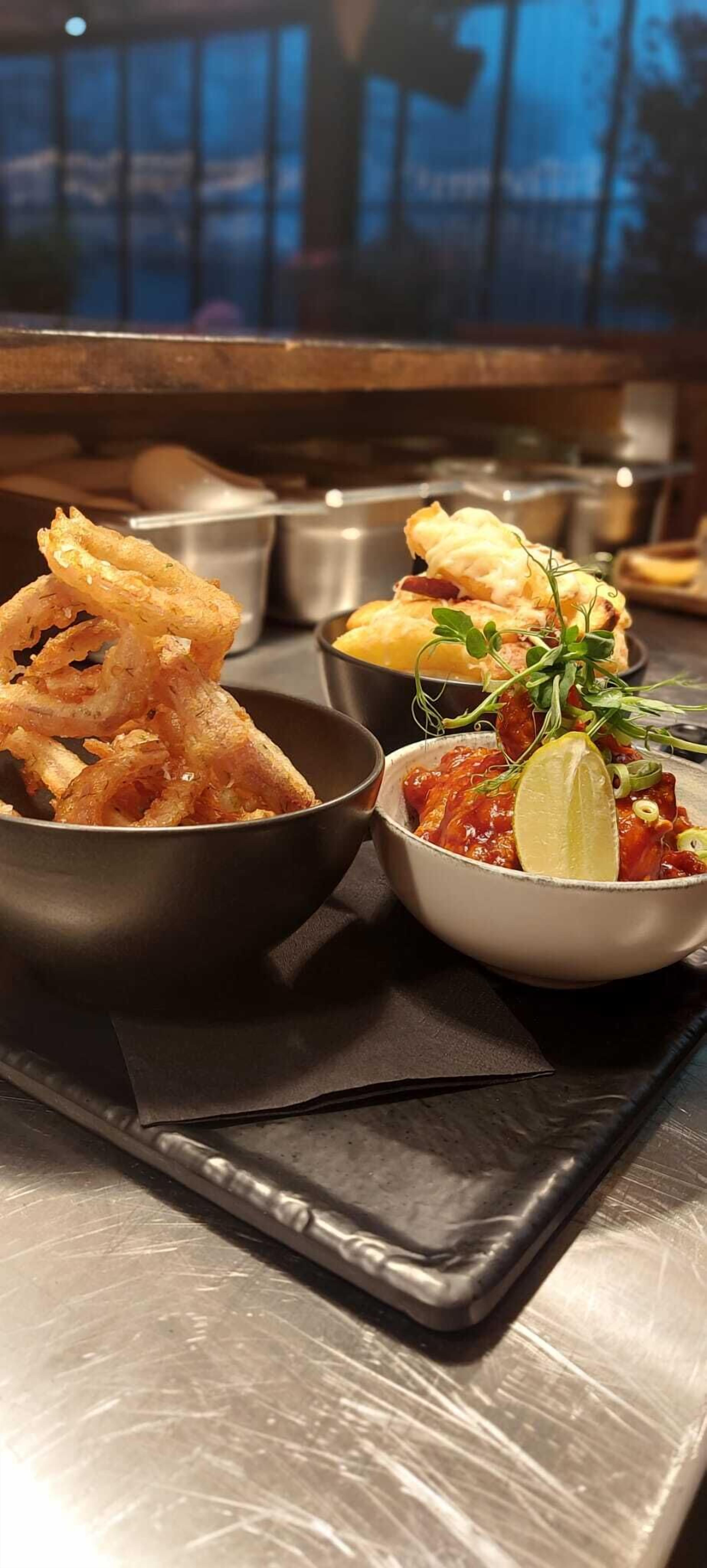 A tray with two bowls of food, one containing fried items and the other a salad with a lime wedge.