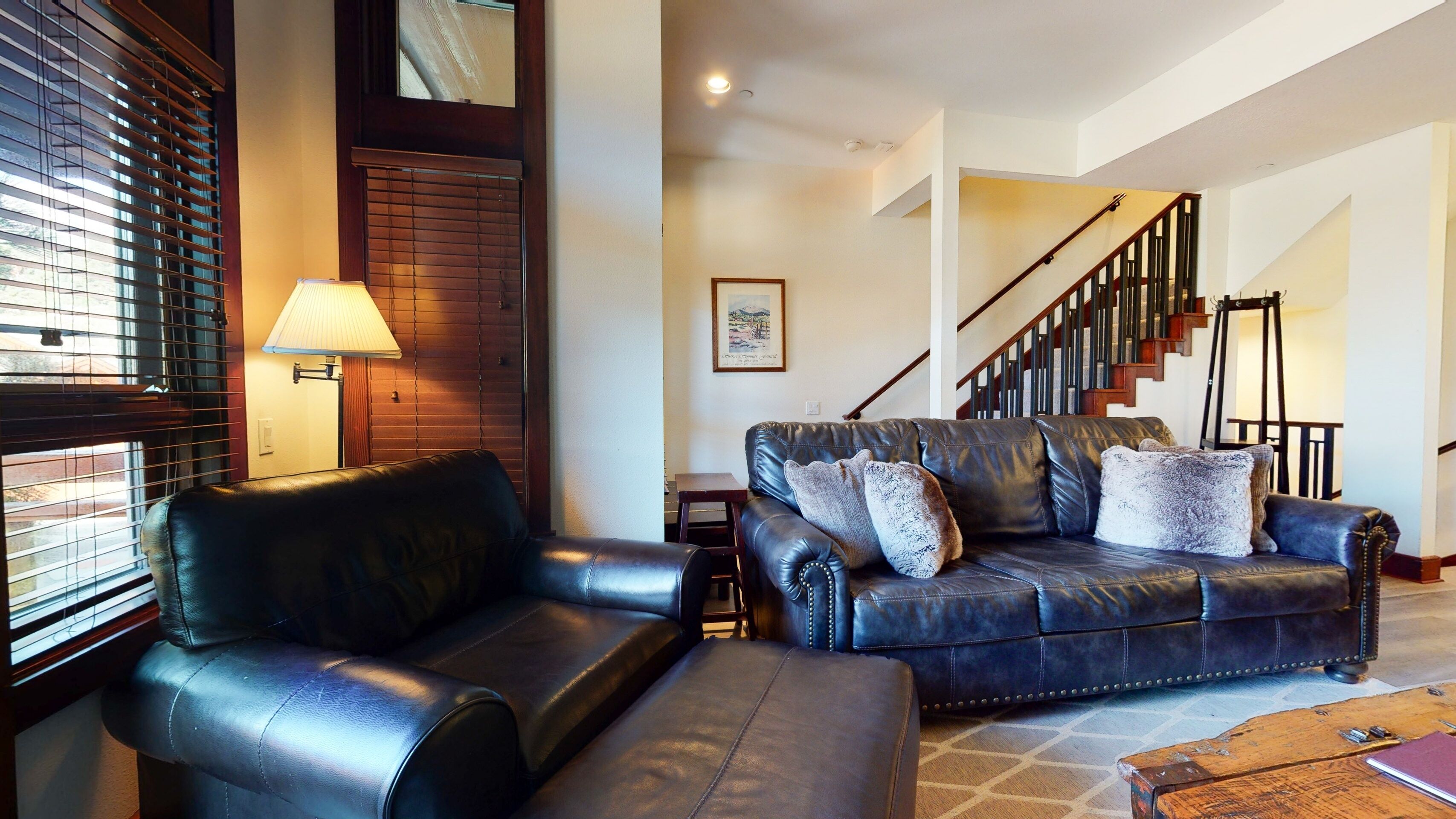 A living room with a leather sofa, a wooden coffee table, and a lamp.