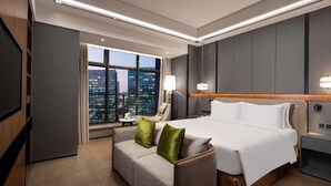 A modern hotel room with a large bed, a sofa, a TV, and a city view. - Holiday Inn Hangzhou Binjiang (Hangzhou)
