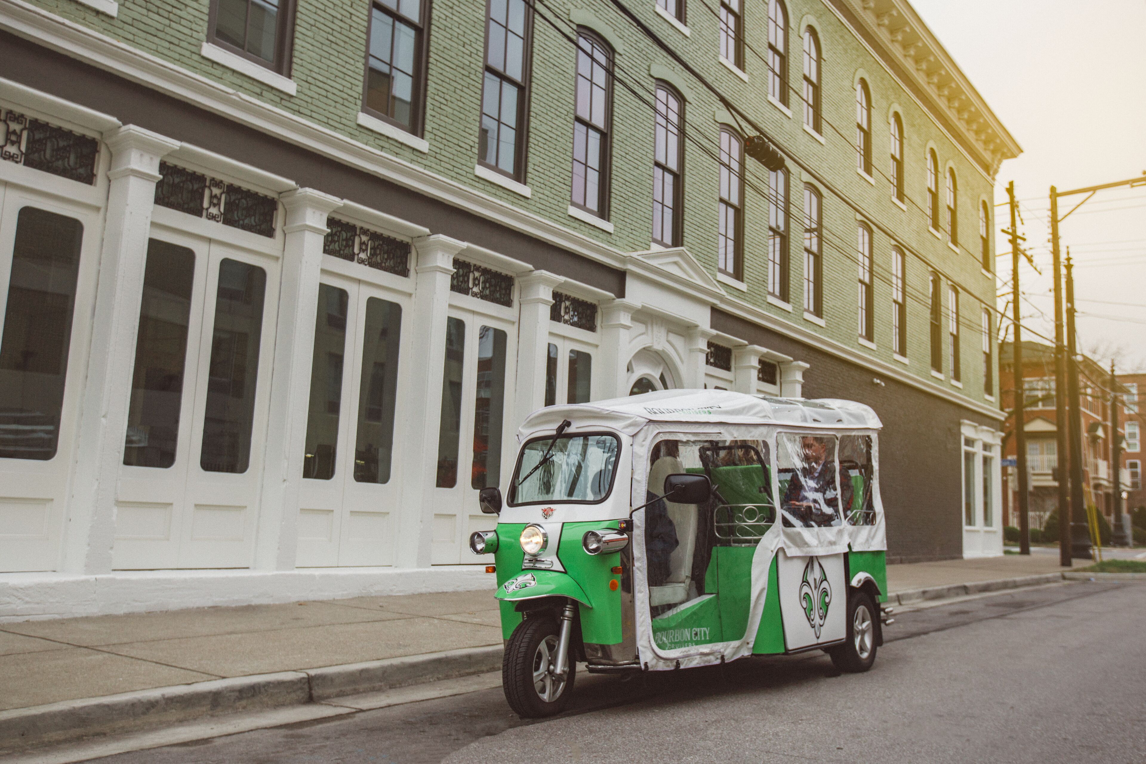Un tuk-tuk vert et blanc est garé dans une rue.