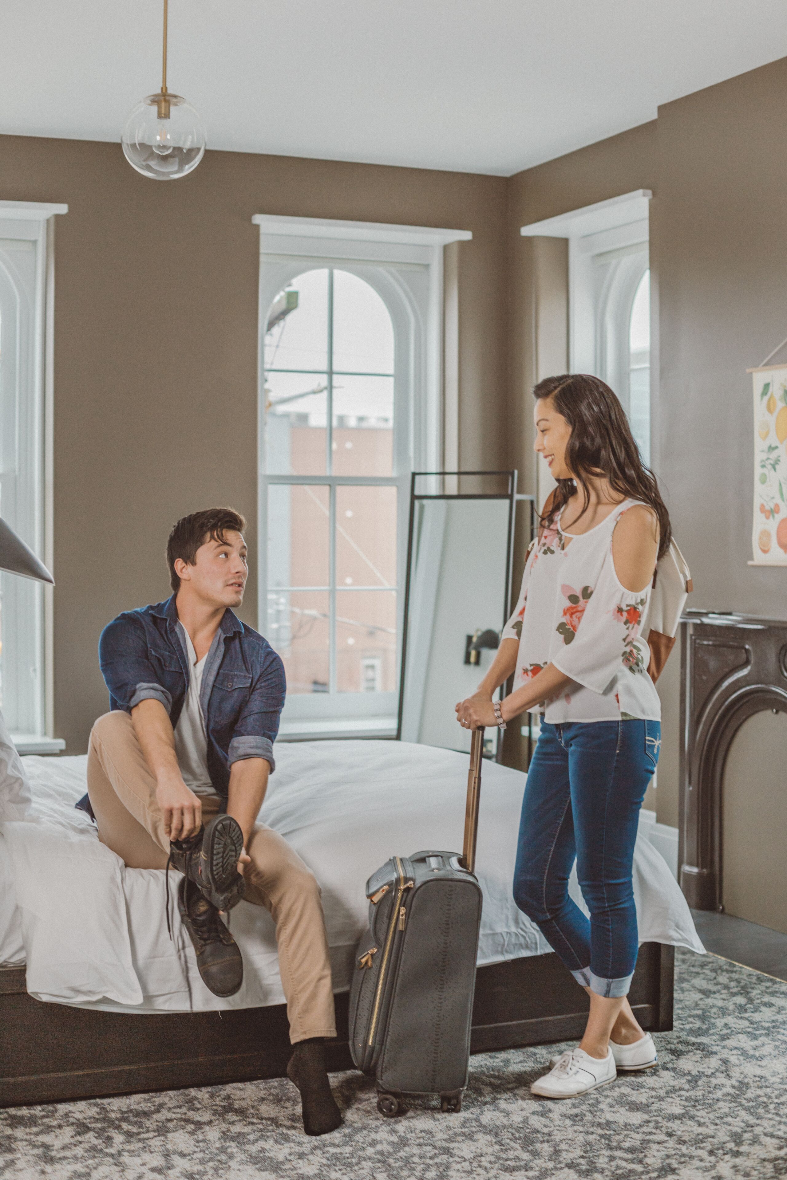A bedroom with a bed, a suitcase, and a person sitting on the bed.
