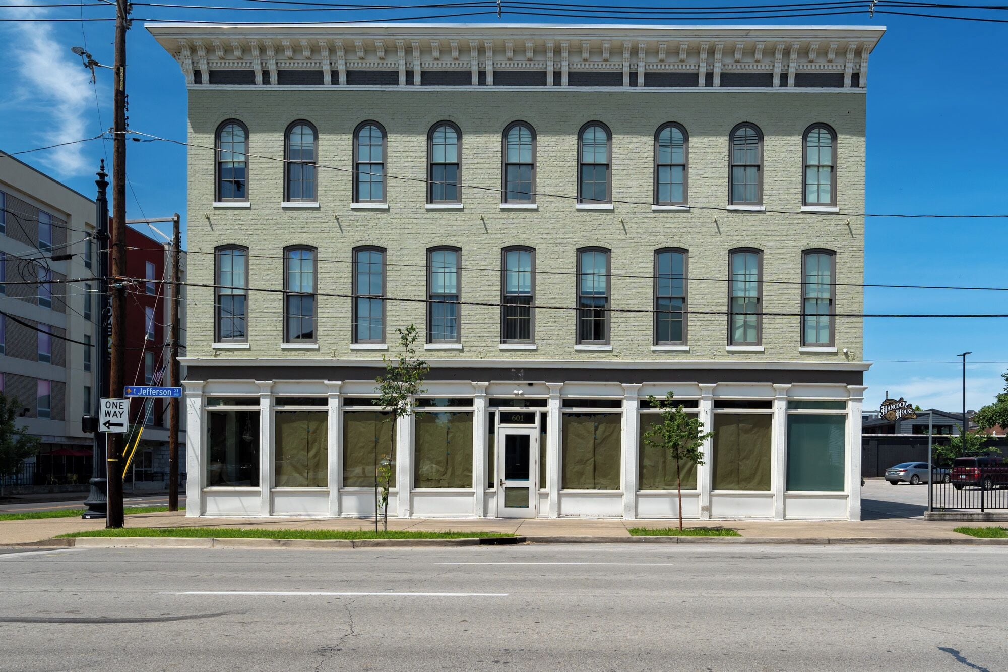 A two-story building with a row of arched windows on the ground floor and a flat facade on the upper floor.