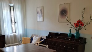 Uma sala de jantar com mesa e cadeiras de madeira, um armário de madeira escura e uma janela com cortinas.
