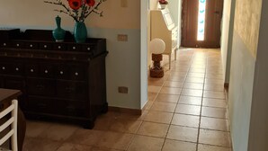 Um corredor com piso de azulejos, um armário de madeira escura e um vaso com flores.