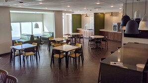Un restaurante moderno con una mezcla de asientos tipo cabina y mesas, una zona de cocina e iluminación colgante.