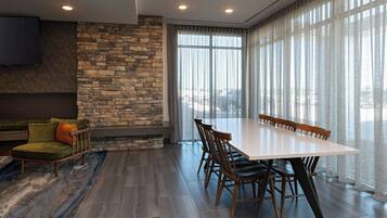 A modern dining area with a stone accent wall, a large window with sheer curtains, and a flat-screen TV mounted on the wall.
