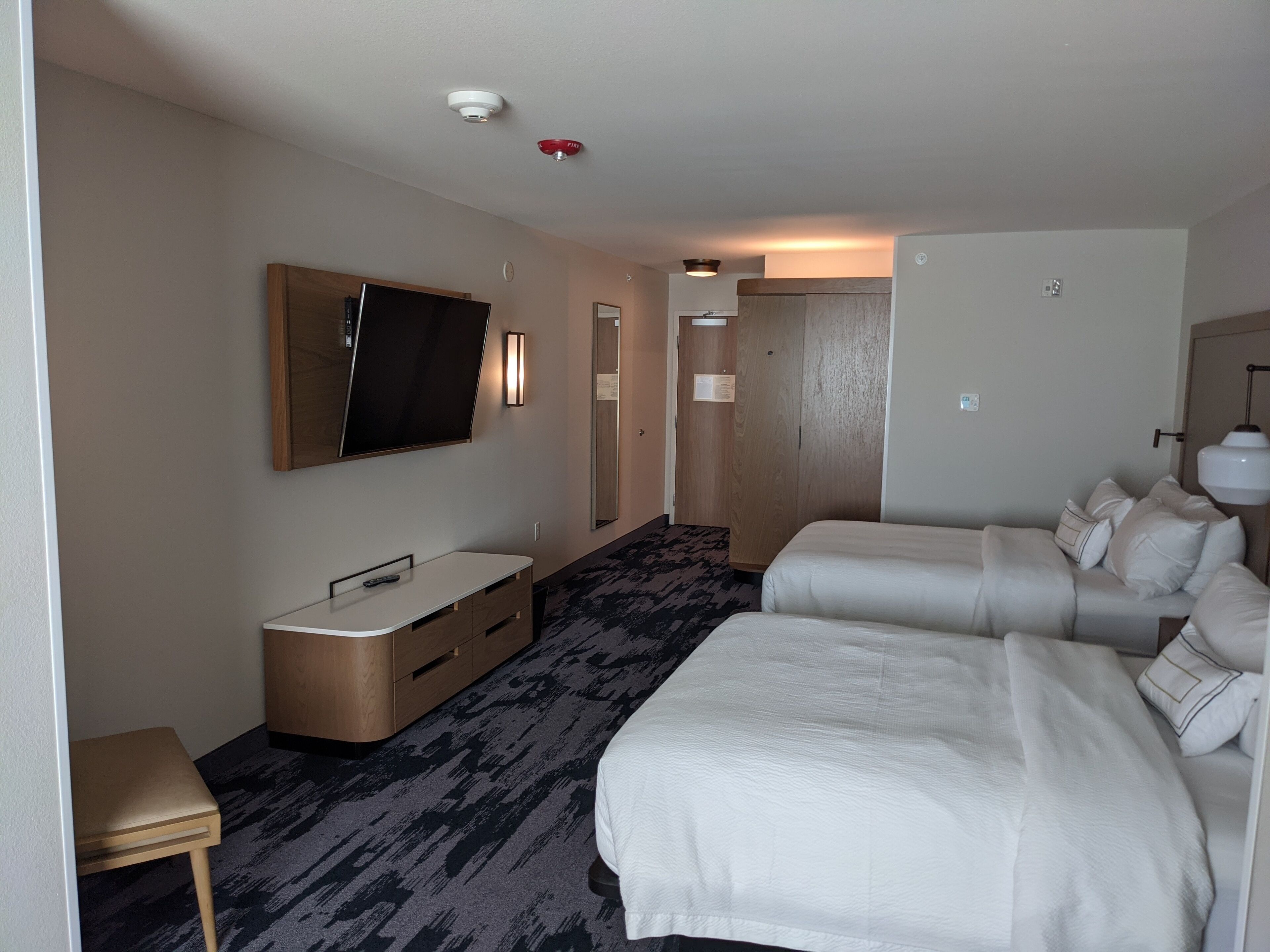 A hotel room with a bed, a desk, a TV, and a wardrobe.