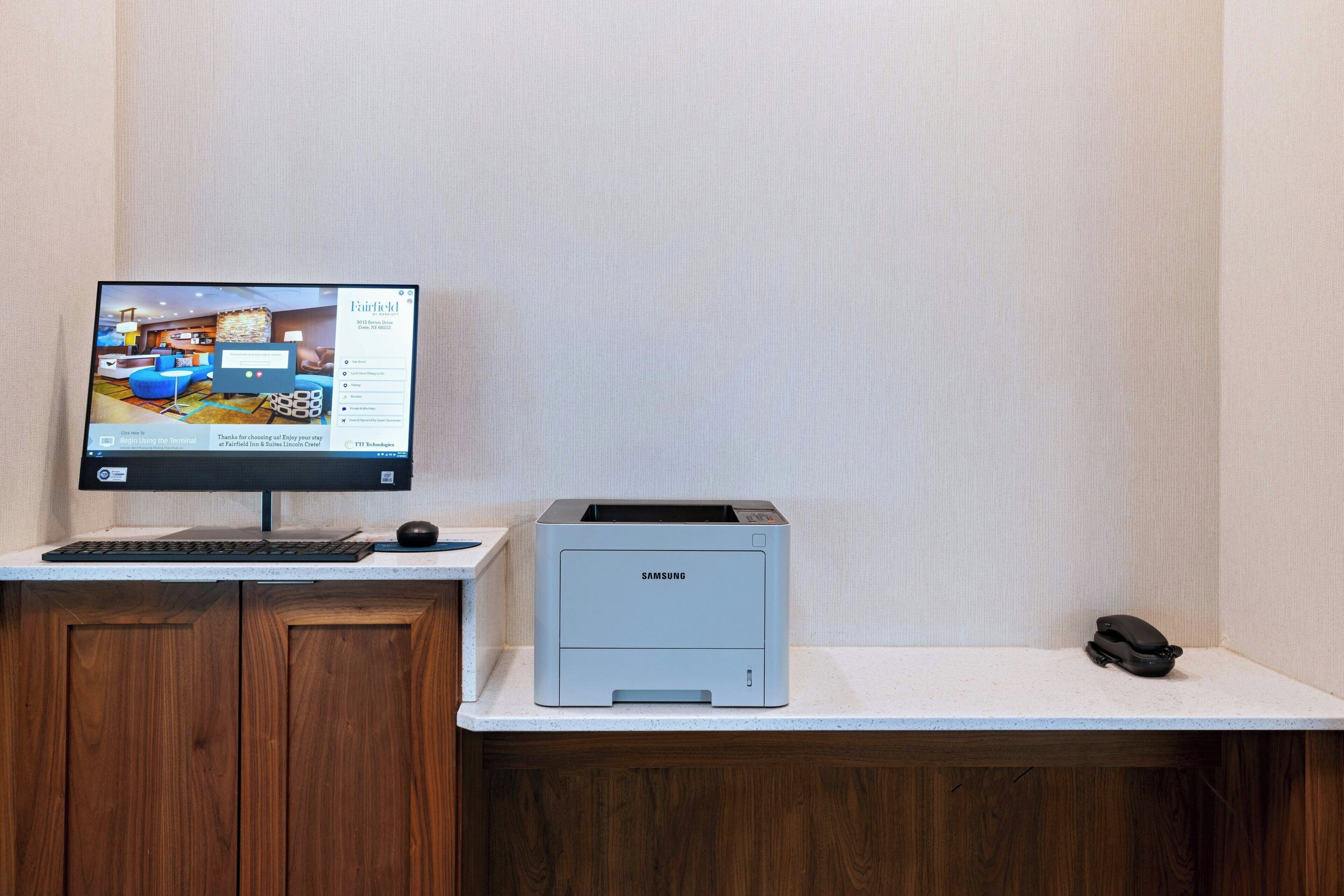 A desktop computer, a printer, and a telephone on a desk with a wooden cabinet underneath.