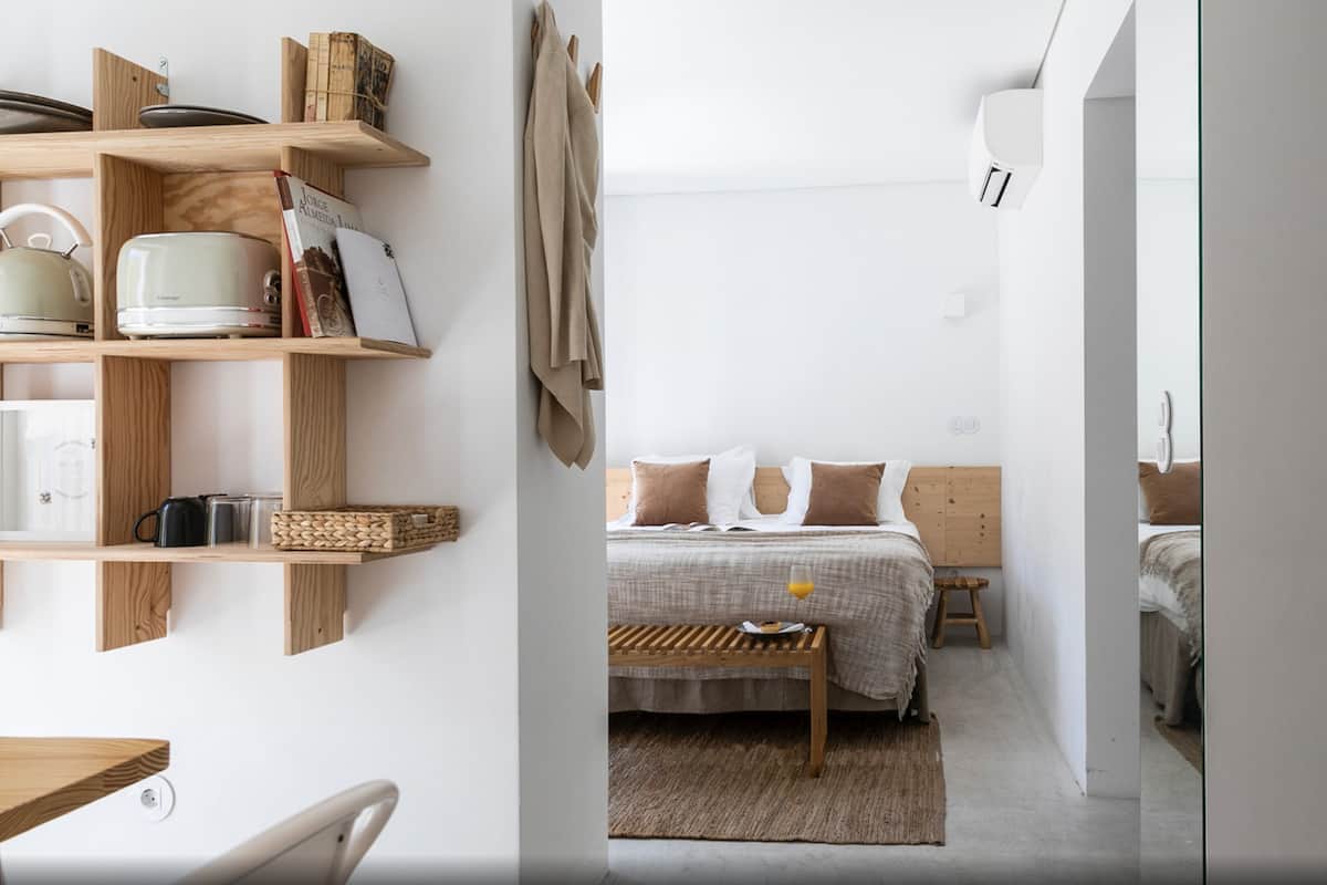 Une chambre moderne avec un lit en bois, une table de chevet et une étagère contenant des ustensiles de cuisine.