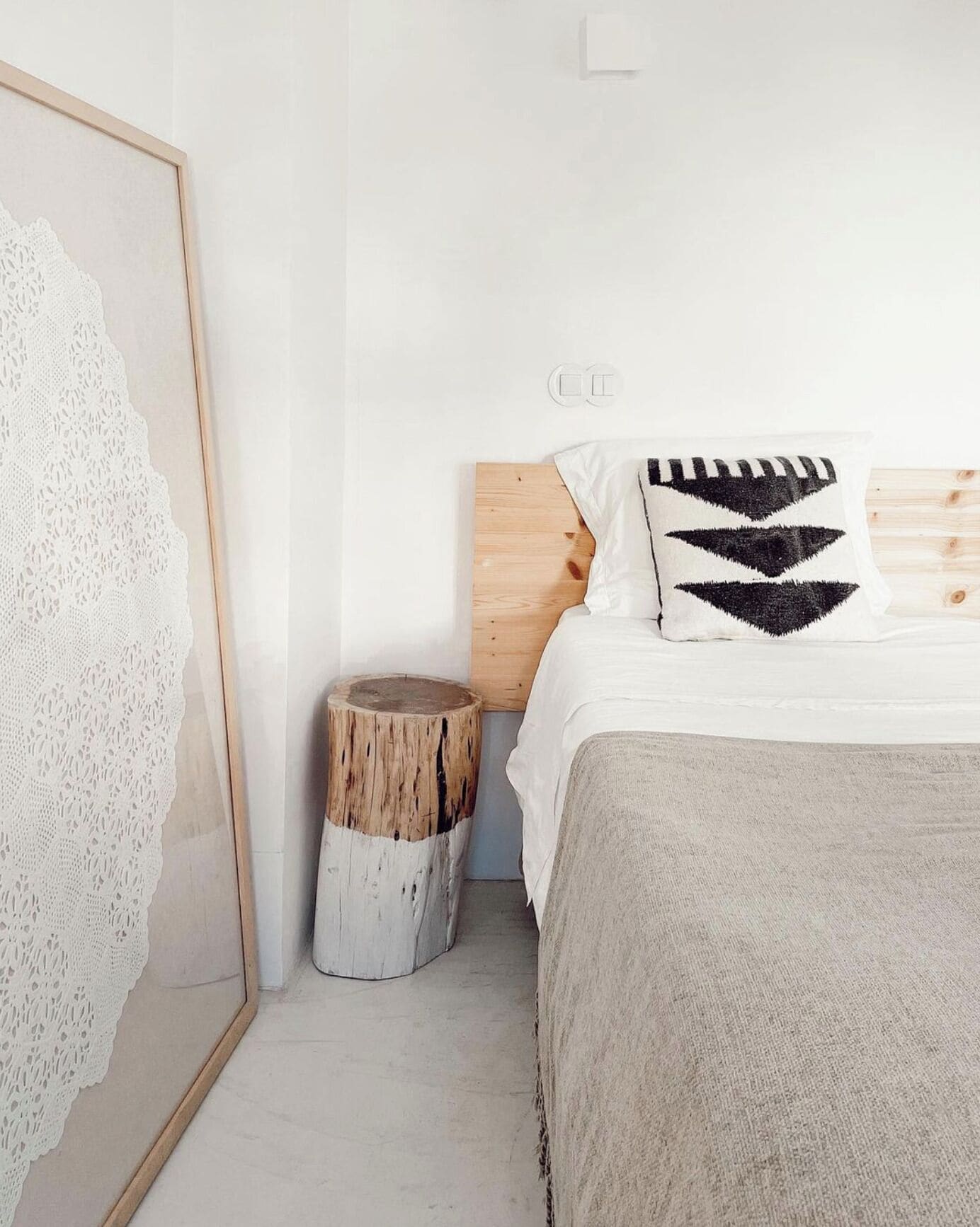A bedroom with a wooden headboard, a white bedspread, and a patterned pillow.