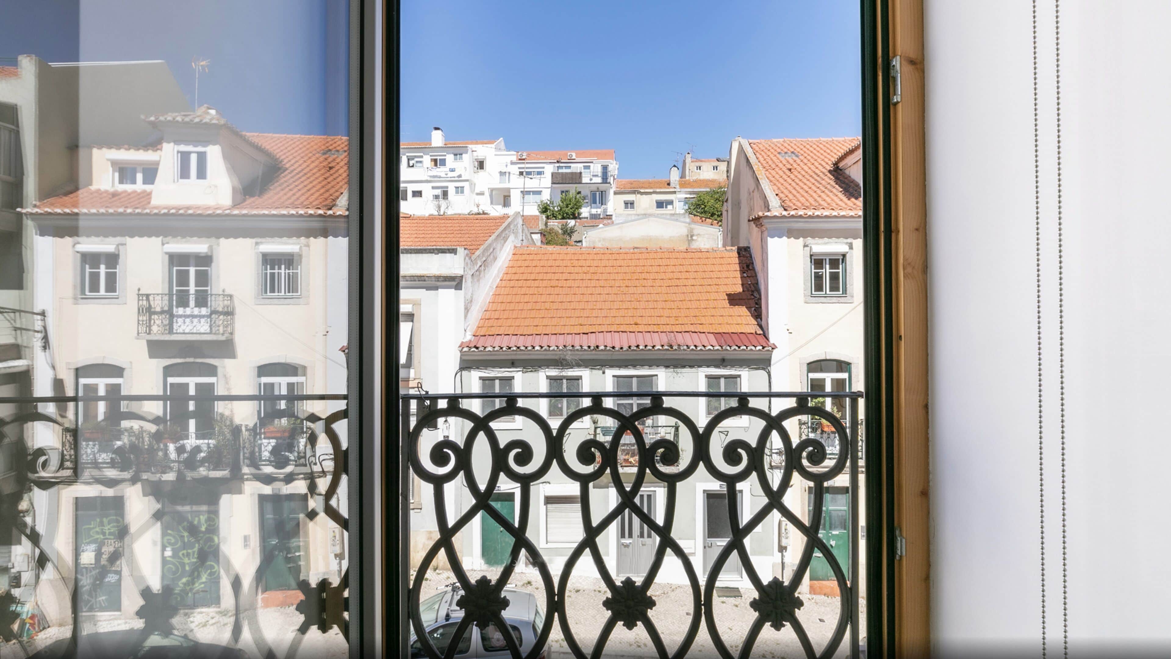 A balcony with wrought iron railings overlooking a street with buildings.