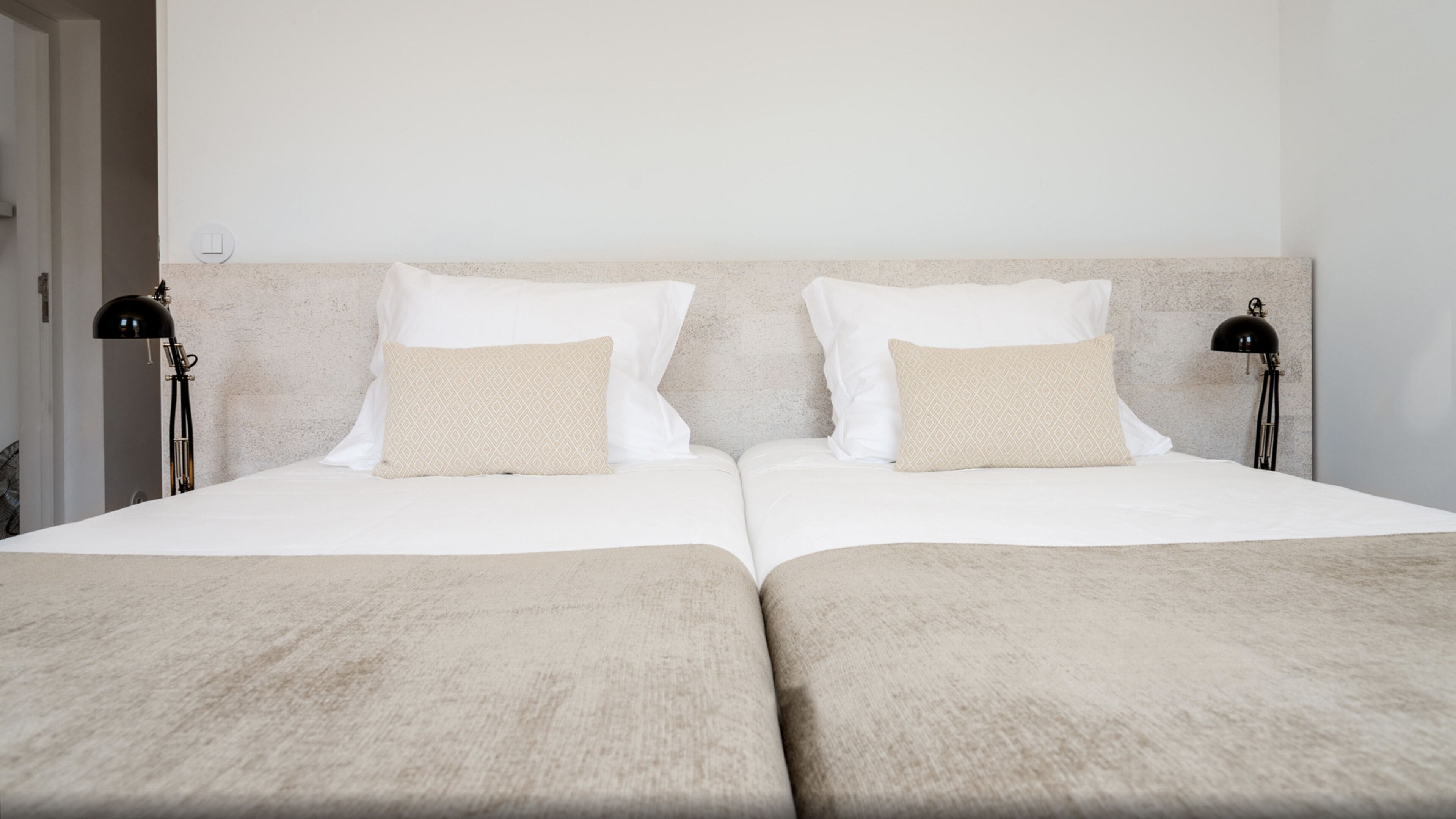 A double bed with two pillows, a headboard, and two bedside lamps.
