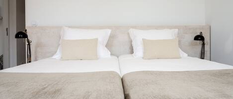 A double bed with two pillows, a headboard, and two bedside lamps.